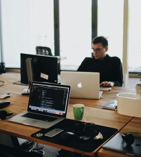 A web developer working on code in a modern office setting with multiple devices.